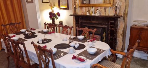 uma mesa de jantar com uma toalha de mesa e cadeiras brancas e uma lareira em Belvedere House em Middleton in Teesdale