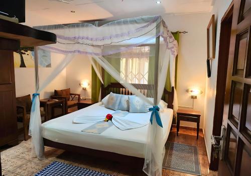 ein Schlafzimmer mit einem weißen Bett mit Baldachin in der Unterkunft Buisson Guesthouse in La Digue
