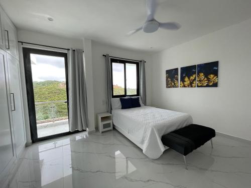 une chambre blanche avec un lit et deux fenêtres dans l'établissement VILLA FLORENCE HOYO CACAO, à Las Terrenas