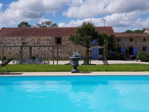 ein Schwimmbad mit Springbrunnen vor einem Gebäude in der Unterkunft Le Clos du Gâts Gîte de charme en Vendée à 15 mn du Parc du Puy duFou in La Gaubretière