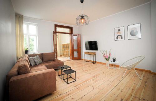 a living room with a brown couch and a wooden floor at Apartament Haffnera in Sopot