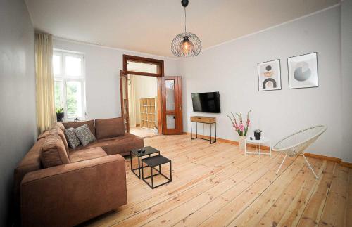 sala de estar con sofá marrón y suelo de madera en Apartament Haffnera, en Sopot