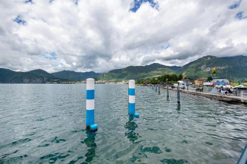 a pier with blue and white poles in the water at Le Volte - Lago D'Iseo in Pisogne