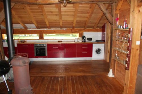 une cuisine avec des armoires rouges et un appareil blanc dans l'établissement Bergerie sur Airial Landais, à Vielle-Saint-Girons