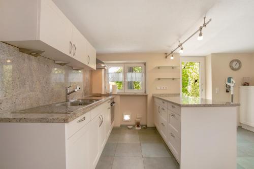 a kitchen with white cabinets and a sink at Allgäuperle mit Hauskater Moritz in Altusried
