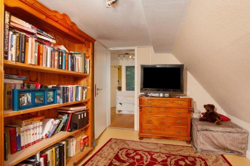 a room with a tv on a dresser next to books at Ferienhaus Allgäuperle in Altusried