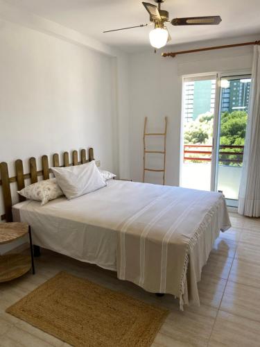 Schlafzimmer mit einem großen weißen Bett und einem Fenster in der Unterkunft Apartamento en Voramar a 2 minutos de la playa in Benicàssim