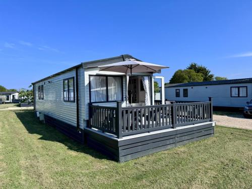 a mobile home with a porch and an umbrella at Stylish 3-bed Mobile Home on St Helen's Coastal Resort, Isle of Wight in Saint Helens