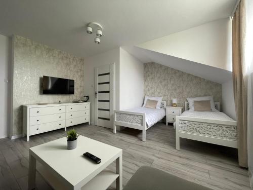 a white bedroom with two beds and a tv at Horse Ville in Pawłów