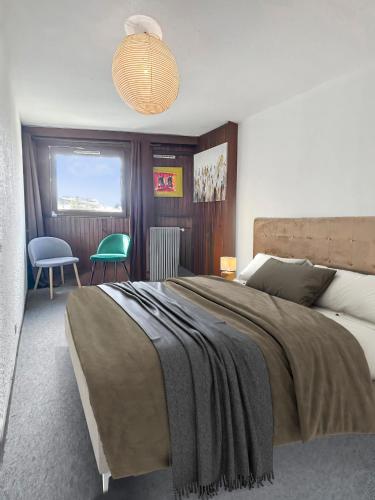 a bedroom with a large bed and a green chair at Refuge Montagnard à Montgenèvre in Montgenèvre