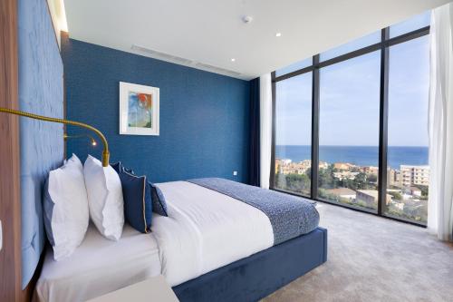 a bedroom with blue walls and a bed with a large window at Hôtel Ben Aouda & Spa in Tipaza