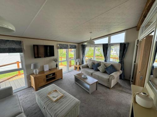 een woonkamer met een bank en een tv bij Bluebell Luxury 2 Bedroom Lodge at Southview Holiday Park in Skegness