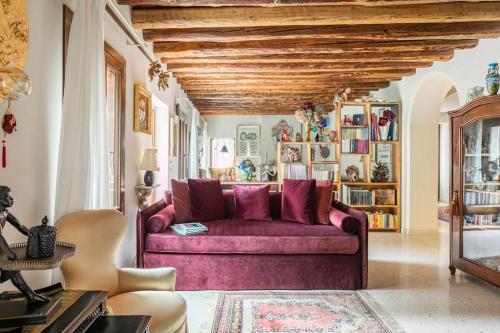 Cinqueteste Luxury Home في البندقية: غرفة معيشة مع أريكة أرجوانية وسقف خشبي