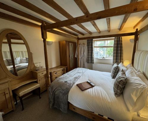 a bedroom with a large bed and a mirror at Guiting Guest House in Guiting Power