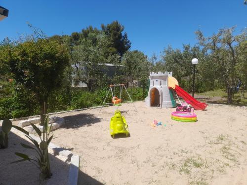 un parque infantil con 2 toboganes y una estructura de juegos en la arena en Villa Elvira, en Vieste