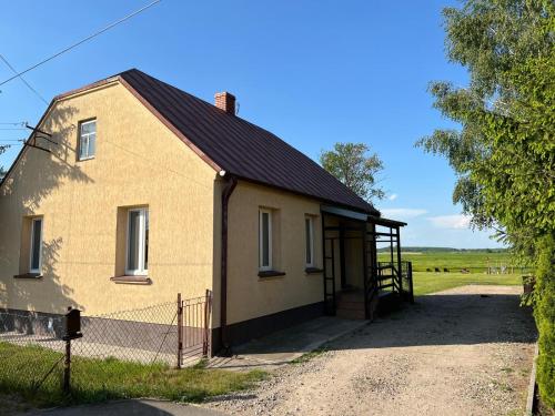 un petit bâtiment avec une clôture à côté d'un champ dans l'établissement Biebrzańskie Zacisze, à Goniądz