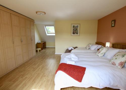 a large white bed in a room with wooden floors at Meadow Rise Guest House in Bourton on the Water