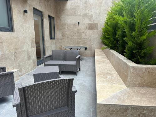 a patio with wicker chairs and a table and a bush at Acacia Avenue Apartments in Is-Swieqi