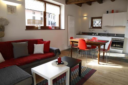 a living room with a red couch and a table at Cjase Dai Fornasirs 2 in Raveo