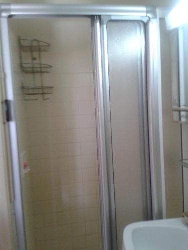 une douche avec une porte vitrée à côté d'un lavabo dans l'établissement Sirmione, à Leucate