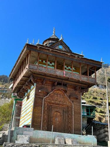 a building with a large wooden door on a hill at SummerHill Riverview Homestay in Sainj