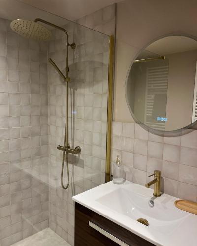une salle de bain avec un lavabo et une douche avec un miroir dans l'établissement Le Moulin de Blanchelande, à Neufmesnil