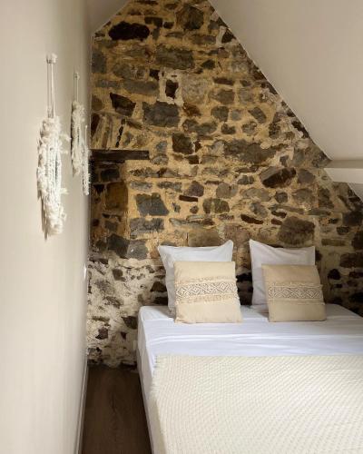 un lit dans une chambre avec un mur en pierre dans l'établissement Le Moulin de Blanchelande, à Neufmesnil