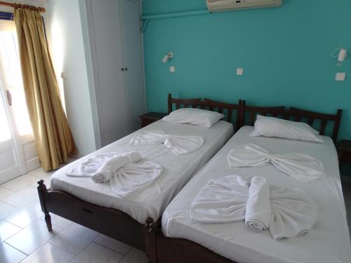 two beds with white towels on them in a room at Hotel Mariona in Pythagoreio