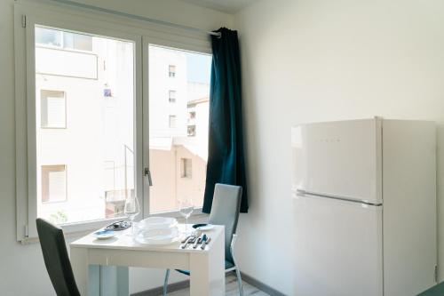 a kitchen with a table and a refrigerator and a window at FG Vacanze in Alghero