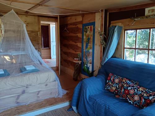 sypialnia z niebieskim łóżkiem i kanapą w obiekcie Quinta da Fornalha - Santuario Agroecologico w mieście Castro Marim