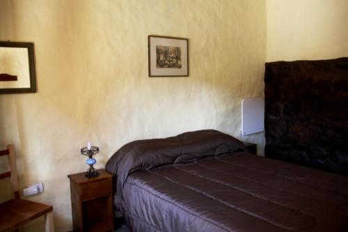 ein Schlafzimmer mit einem Bett und einem Tisch mit einer Lampe in der Unterkunft Postales del Tiempo in Tilcara