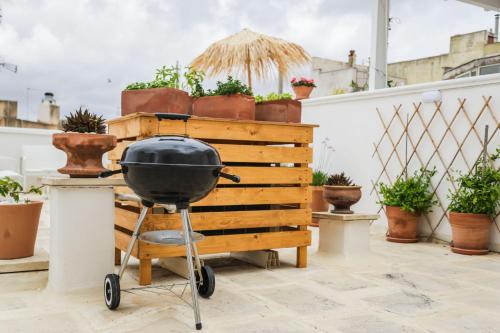 a grill sitting on a patio with potted plants at Sea Suites in Ugento