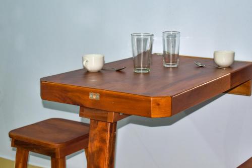 un tavolo in legno con 3 bicchieri e 2 sedie di Cabinas Ecologicas Rio Brasil a Tabores