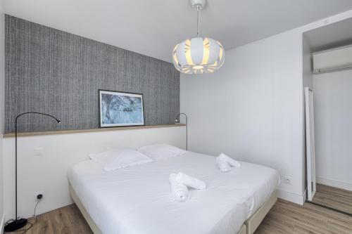 um quarto com uma cama com lençóis brancos e um lustre em The Lake Terrace em Annecy