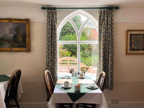 ein Esszimmer mit einem Tisch und einem Fenster in der Unterkunft The Cottage Guest House in Bishops Stortford