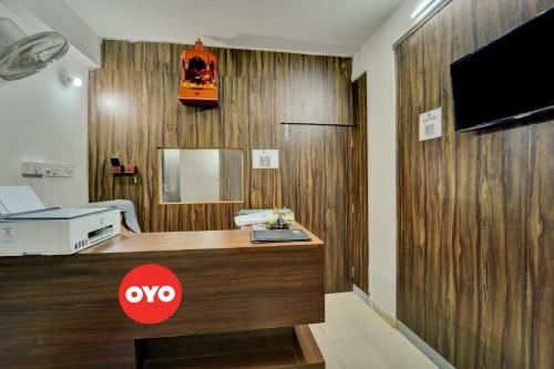 OYO Flagship Hotel Celebrate Inn في باتنا: غرفة مع مكتب وتلفزيون على جدار خشبي