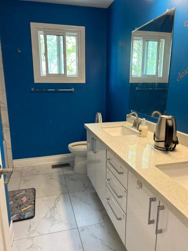 een blauwe badkamer met een toilet en een wastafel bij KenHouse in Toronto