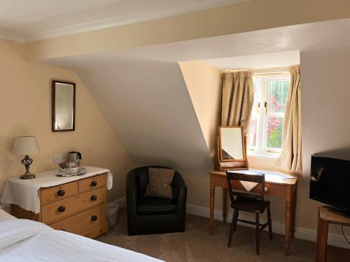 a bedroom with a bed and a desk and a chair at The Cottage Guest House in Bishops Stortford