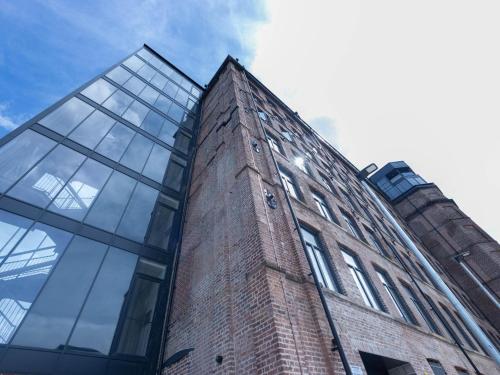 a brick building with glass windows on the side of it at Leeds Haven Niche 1 2 Bedroom Apartments with Cityscape views by Belvilla in Leeds