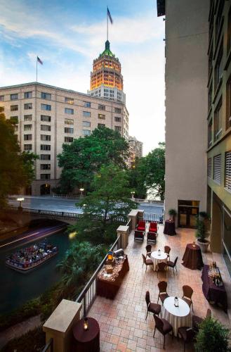 a balcony of a building with tables and chairs and a river at Hotel Contessa - Suites on the Riverwalk in San Antonio