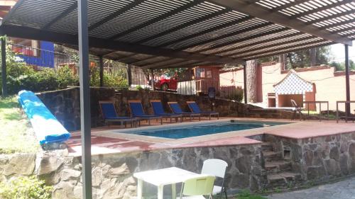 una piscina con sillas azules y una sombrilla en Departamentos en Avandaro, en Valle de Bravo