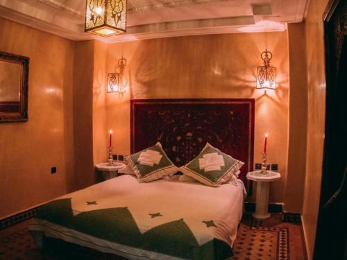 een slaapkamer met een bed met 2 tafels en 2 kaarsen bij Riad Golf Stinia in Meknès
