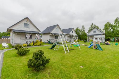 a yard with a playground in front of a house at Biale Domki Kopalino in Kopalino