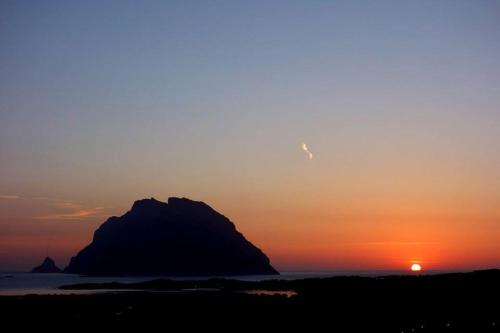 a sunset with a large rock in the ocean at Porto San Paolo a 50 mt dal mare in Porto San Paolo