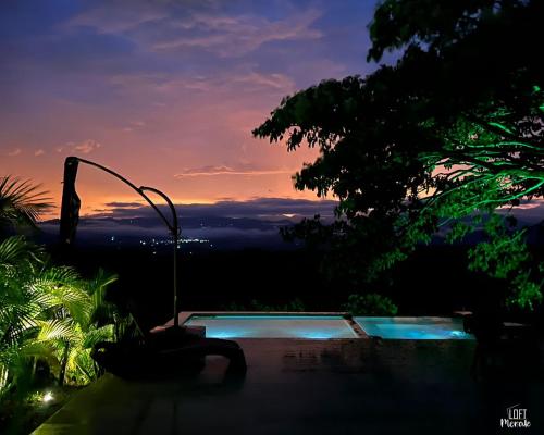 a swimming pool with a sunset in the background at LoftMerak in Pereira