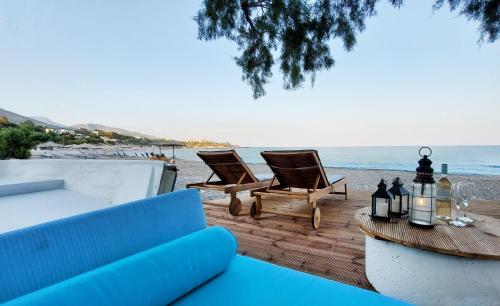 a patio with two chairs and a table on the beach at Varkospito in Ierápetra