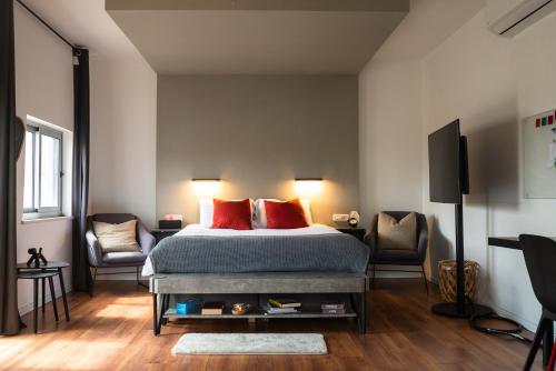 1 Schlafzimmer mit einem Bett mit roten Kissen und 2 Stühlen in der Unterkunft Central Charming Studio Apartment in Jerusalem in Jerusalem