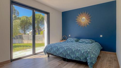 - une chambre dotée d'un mur bleu avec un lit et une fenêtre dans l'établissement Villa contemporaine avec piscine - 170m2, à Sauzet