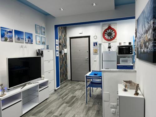 a living room with a large television and a kitchen at Blue House in Marina di Fuscaldo