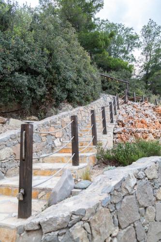 a stone retaining wall with a fence and stairs at Varkospito in Ierápetra
